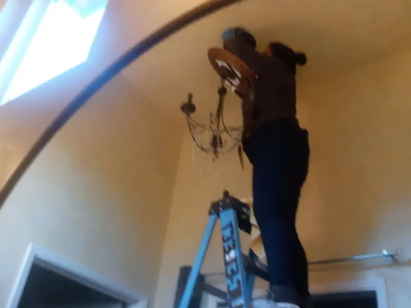 Electrician installing a chandelier in a Creswell residence